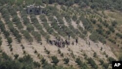 A group of Syrians head towards Turkey as they wait for the authorization to cross the border near Turkish village of Guvecci in Hatay province, Turkey, June 8, 2011