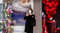 Un empleado usa una máscara facial mientras está parada afuera de una tienda en un centro comercial en su mayoría vacío en Beijing, el sábado 7 de marzo de 2020.