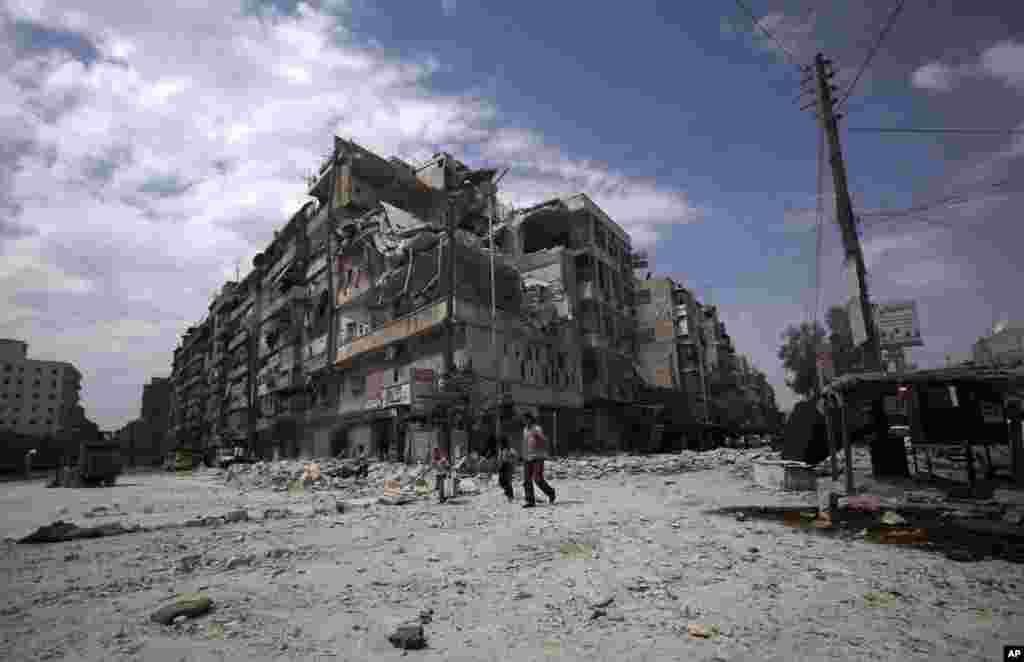 Syrians walk by a building which was damaged by government airstrike in Aleppo, Syria, September 11, 2012. 
