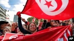 People hold Tunisian flags as they demonstrate two days after gunmen attacked the museum and killed scores of people in Tunis, Tunisia, March 20, 2015. 