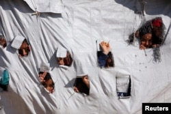 Children look through holes in a tent at al-Hol displacement camp in Syria, April 2, 2019.