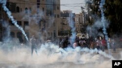 Para demonstran Palestina berlarian dari gas air mata yang ditembakkan oleh tentara Israel dalam bentrokan dekat Ramallah, Tepi Barat (17/10). (AP/Majdi Mohammed)