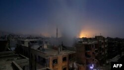 Smoke billows from a building early, Oct. 30, 2015, following reported shelling by Syrian government forces in the rebel-controlled area of Douma, east of Damascus. 