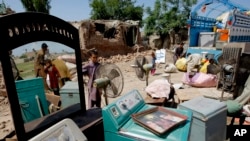 FILE - Afghan refugees who fled their country due to war, collect their belongings after Pakistani authorities demolished their home in suburbs of Peshawar, May 1, 2015.