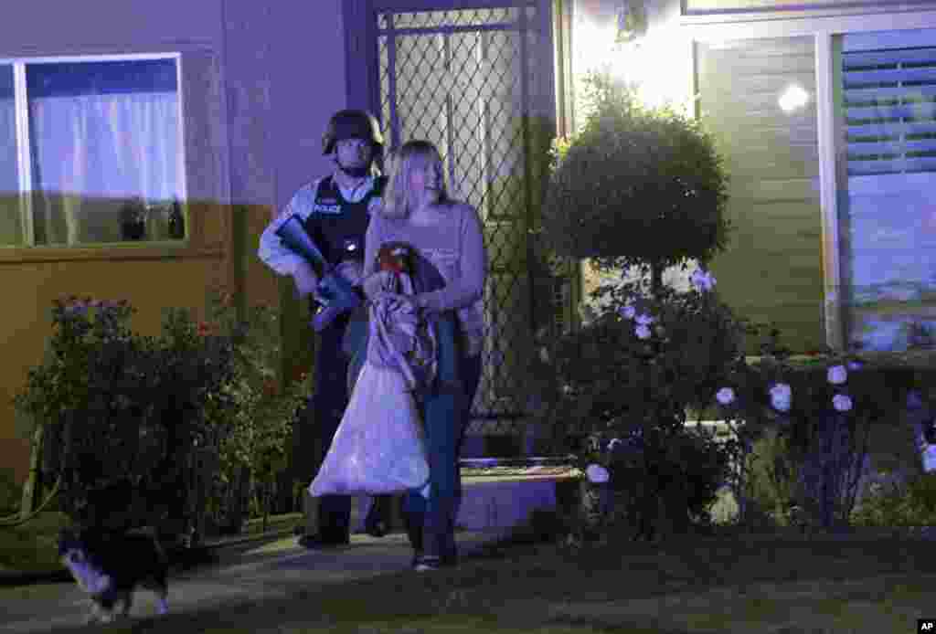A police officer escorts a woman from a home on Dec. 2, 2015, in Redlands, California, following a shooting that killed multiple people at a social services center for the disabled in San Bernardino.