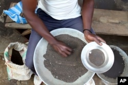 FILE - A Congolese miner sifts through ground rocks to separate out the cassiterite, the main ore that’s processed into tin, in the town of Nyabibwe, Congo.