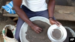FILE - A Congolese miner sifts through ground rocks.
