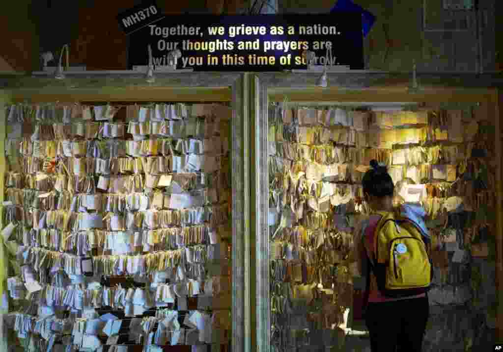 A woman ties a message card for passengers onboard the missing Malaysia Airlines Flight 370 at a shopping mall in Petaling Jaya, near Kuala Lumpur, Malaysia, April 10, 2014.