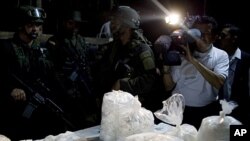 A members of the press photographs packages of seized cocaine during a drug presentation by police in Puerto Gaitan, some 150 miles southeast of Bogota, Colombia, Oct. 13, 2011.