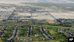 FILE - This aerial file photo shows lush green golf courses bordering the edge of the desert in Palm Springs, California, April 3, 2015. 