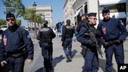 Police officers and riot police officers, right, patrol on the Champs Elysees boulevard in Paris, April 21, 2017. 