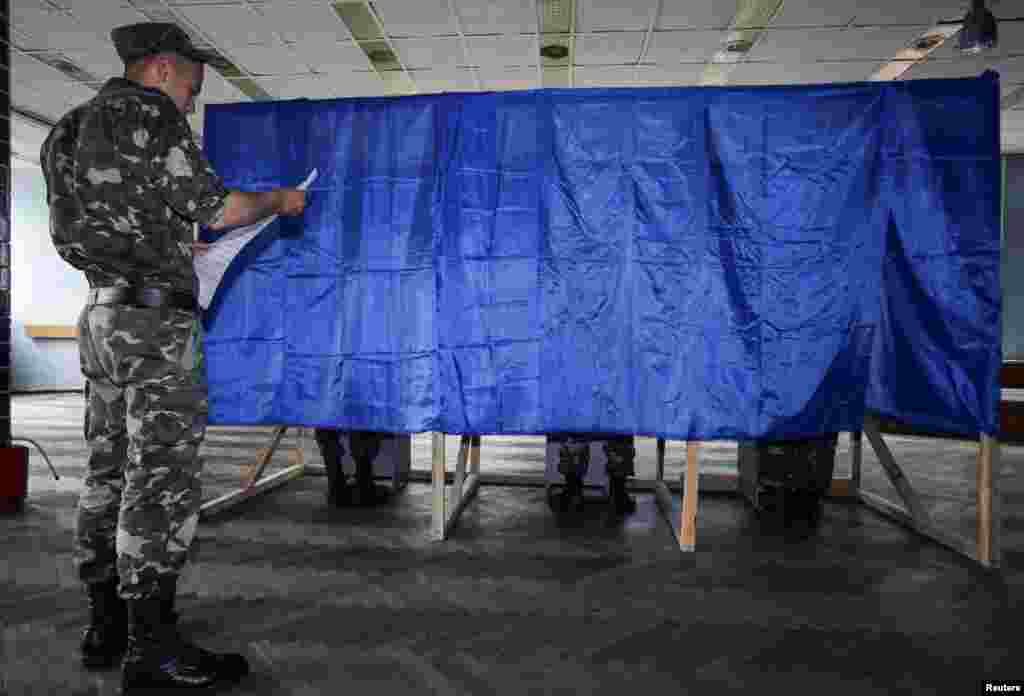 A Ukrainian soldier waits outside voting booths during voting in the village of Desna in the Chernihiv region of Ukraine, May 25, 2014.