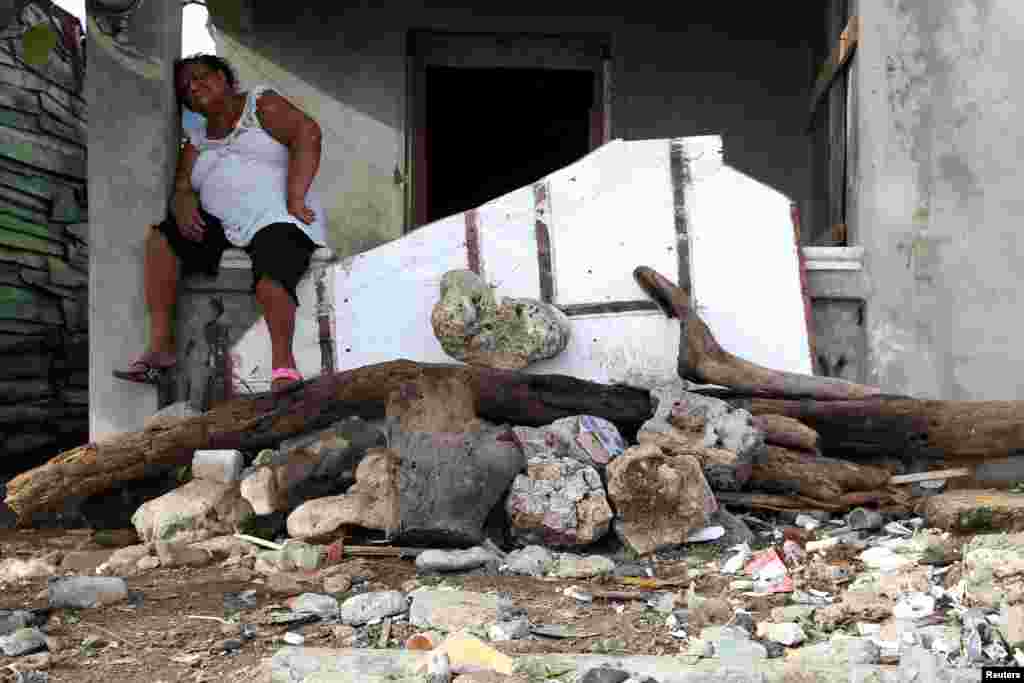 A woman takes a break from cleaning the debris in front of a house, in the aftermath of Hurricane Irma in Puerto Plata, Dominican Republic.