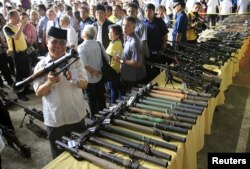 FILE - Philippine President Benigno Aquino (far L) talks to a religious leader while Al-haj Murad Ebrahim (2nd L), chairman of the Moro Islamic Liberation Front (MILF), inspects a B40 rocket launcher during the Ceremonial Turnover of Weapons and Decommissioning.