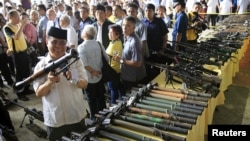 Philippine President Benigno Aquino (far L) talks to a religious leader while Al-haj Murad Ebrahim (2nd L), chairman of the Moro Islamic Liberation Front (MILF), inspects a B40 rocket launcher during the Ceremonial Turnover of Weapons and Decommissioning 