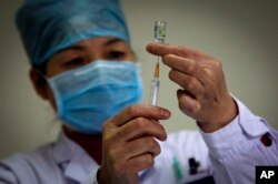 FILE - A health worker prepares a dose of H1N1 vaccine at the start of a free vaccination program intended for all Beijing residents at a clinic in Beijing.