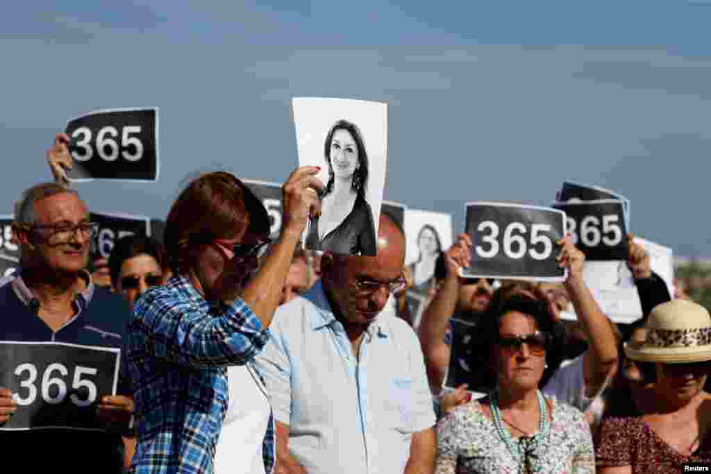 People attend three minutes of silence as they gather at the site where anti-corruption journalist Daphne Caruana Galizia was assassinated in a car bomb one year ago, in Bidnija, Malta.