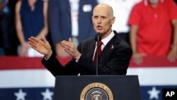 Florida Gov. Rick Scott gestures as he appears with President Donald Trump during a rally, Oct. 31, 2018, in Estero, Fla. Scott is running for U.S. Senate against Democrat Bill Nelson.