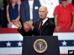 Florida Gov. Rick Scott gestures as he appears with President Donald Trump during a rally, Oct. 31, 2018, in Estero, Fla. Scott is running for U.S. Senate against Democrat Bill Nelson.