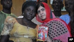 Pakistani activist Malala Yousafzai who survived being shot by the Taliban because she advocated education for girls, holds a picture of kidnapped schoolgirl Sarah Samuel with her mother Rebecca Samuel, during a visit to Abuja, Nigeria, July 13, 2014. 