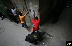 FILE - A man is frisked by a Baruta municipal police officer during a routine patrol through a Caracas shanty town, Jan. 18, 2007.