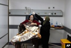 In this Friday, Jan. 22, 2021 file photo, a woman combs the hair of her sister, a COVID-19 patient, at the intensive care unit of the Rafik Hariri University Hospital in Beirut, Lebanon. (AP Photo/Bilal Hussein, file)