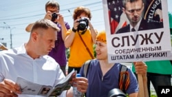 Russian opposition activist and blogger Alexei Navalny, left, speaks to activists of a National Liberation movement holding a poster with a portrait of him and words reading "Serve United States of America" during his visit in Novosibirsk, Russia, Sunday,