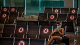 In this June 30, 2020, file photo, a passenger sits at Barcelona airport in Barcelona, Spain. (AP Photo/Emilio Morenatti)