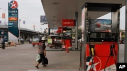 FILE PHOTO - A woman walks through a closed Caltex gas station during a strike Monday, May 12, 2014, in Phnom Penh, Cambodia.