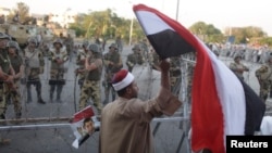 2013年7月7日，在埃及首都开罗，下台的穆尔西总统的支持群众连续3天进行抗议示威，有人高举埃及国旗表示支持穆尔西。