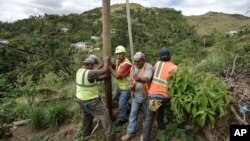 Public Works Sub-Director Ramon Mendez, wearing hard hat, directs locals who are municipal workers, Eliezer Nazario, holding rope, Tomas Martinez, right, and Angel Diaz, left, as they install a power pole in an effort to return electricity to Felipe Rodriguez's home, four months after Hurricane Maria in Coamo, Puerto Rico, Jan. 31, 2018.