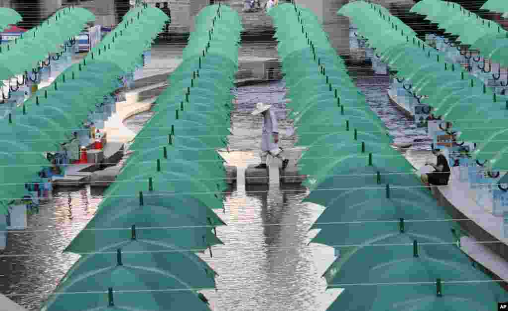 A Buddhist monk walks under umbrellas that appear over the Cheonggye stream, during a campaign to raise money to help children in need, in Seoul, South Korea.