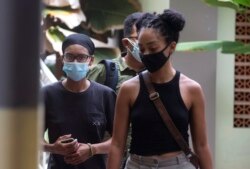 Desainer grafis Amerika Kristen Antoinette Grey (kiri) berjalan bersama rekannya Saundra Michelle Alexander (kanan) untuk tes COVID-19 di sebuah rumah sakit di Denpasar, Bali, Rabu, 20 Januari 2021.