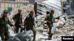 FILE - Forces loyal to Syria's President Bashar al-Assad walk with their weapons past rubble after they advanced on the southern side of the Castello Road in Aleppo, Syria, in this handout picture by SANA, July 28, 2016.