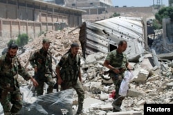 Forces loyal to Syria's President Bashar al-Assad walk with their weapons past rubble after they advanced on the southern side of the Castello road in Aleppo, Syria, in this handout picture provided by SANA on July 28, 2016.