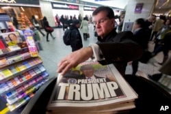 FILE - A man reaches for the New York Post newspaper featuring president-elect Donald Trump's victory, Nov. 9, 2016, in New York.