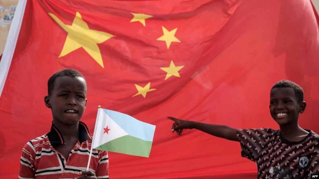FILE - A boy holds the Djiboutian national flag in front of the Chinese national flag before the launching ceremony of China-financed 1,000-unit housing construction project in Djibouti, July 4, 2018. 