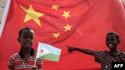 2018年7月4日，在吉布提舉行的中國資助的1,000個住房建設項目啟動儀式前，一名男孩在中國國旗前舉著吉布提國旗。