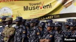 Policemen stand in front of an election banner of Uganda's President Yoweri Museveni in Kampala, Uganda, Feb. 15, 2016.