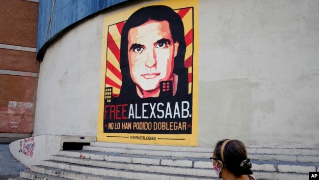 A woman walks near a poster asking for the freedom of Colombian businessman and Venezuelan special envoy Alex Saab, in Caracas, Venezuela, Oct. 16, 2021.