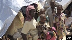 Somalis displaced by famine sit in their makeshift shelters in Mogadishu, Somalia, Friday, July 22, 2011