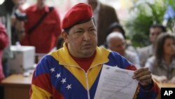 El presidente de Venezuela, Hugo Chávez, enseña la credencial que lo acredita como candidato presidencial tras inscribirse este 11 de junio.