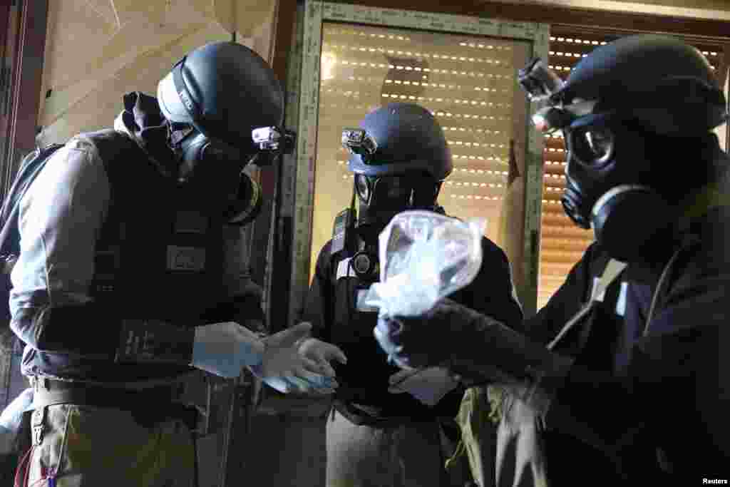 A U.N. chemical weapons expert, wearing a gas mask, holds a plastic bag containing samples from one of the sites of an alleged chemical weapons attack in the Ain Tarma neighborhood of Damascus. A team of U.N. experts left their Damascus hotel for a third day of on-site investigations into apparent chemical weapons attacks on the outskirts of the capital.