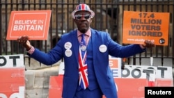 A pro-Brexit supporter holds placards outside the Houses of Parliament, following the Brexit votes the previous evening, in London, March 28, 2019.