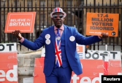 A pro-Brexit supporter holds placards outside the Houses of Parliament, following the Brexit votes the previous evening, in London, March 28, 2019.