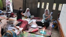 Indonesian teacher Inggit Andini, right, teaches at a makeshift class for students who lack access to the internet to study online, at her residence in Tangerang, Indonesia, on Aug. 10, 2020