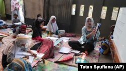 Guru Inggit Andini, kanan, mengajar di kelas darurat bagi siswa yang tidak memiliki akses internet untuk belajar online, di Tangerang, 10 Agustus 2020, sebagai ilustrasi. Empat perempuan, yang sebagian termasuk "berdarah biru" memilih menjadi guru. (Foto: AP)