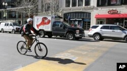 A cyclist pedals over the worn finish line of the Boston Marathon in Boston, April 1, 2015.