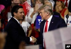 President Donald Trump, right, shakes hands with Florida Republican gubernatorial candidate Ron DeSantis during a rally in Tampa, Fla., July 31, 2018.