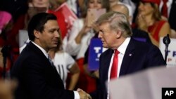 ARCHIVO - El presidente Donald Trump, a la derecha, le da la mano al candidato republicano a gobernador de Florida, Ron DeSantis, durante un mitin en Tampa, Florida, el 31 de julio de 2018.